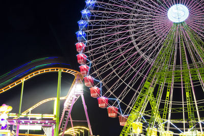 Low angle view of illuminated ferris wheel against sky at night