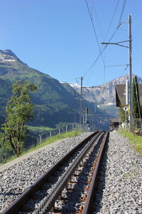 Railroad track by mountain against clear sky