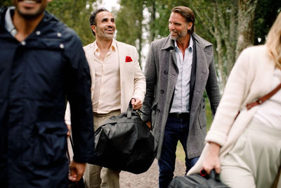 Smiling male professionals walking with colleagues during business trip