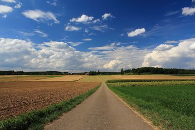 Road amidst field against sky