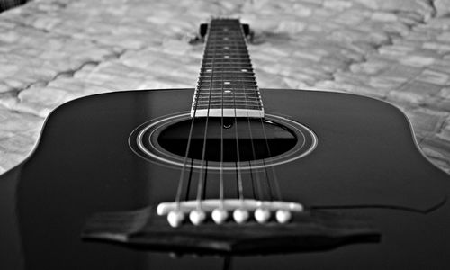 Close-up of acoustic guitar on bed