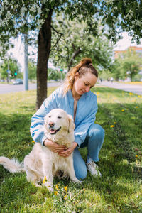 Portrait of young woman with dog on field