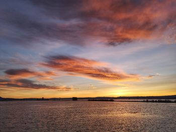 Scenic view of sea against dramatic sky during sunset