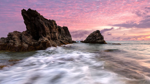 Rock formation on sea against sky during sunset