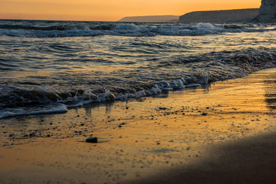 Surface level of beach against sky during sunset