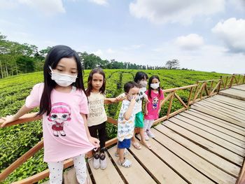 Rear view of women standing on footbridge against sky