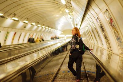 Woman standing on escalator