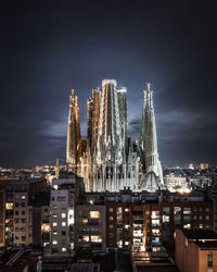 Illuminated buildings in city against sky at night