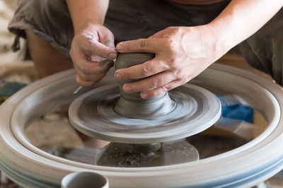 Midsection of man making clay pot