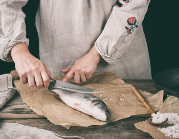 Midsection of woman cutting fish at table