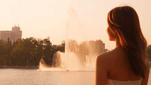 Rear view of woman standing against waterfall