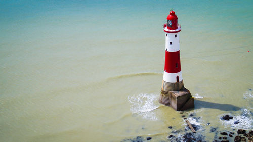 Lighthouse by sea against buildings
