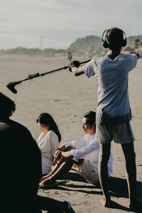 Rear view of people standing on beach