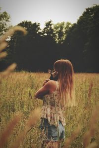 Woman embracing dog while standing amidst field