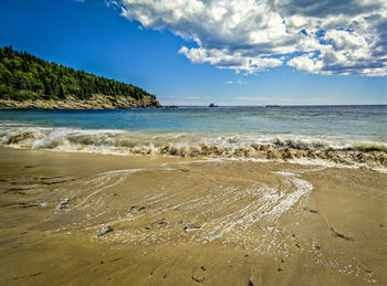 Scenic view of beach against cloudy sky