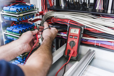 Close-up of man using voltmeter in factory