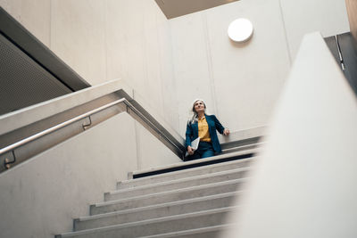 Businesswoman with laptop standing at staircase