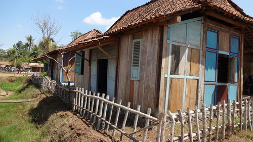 Old house by building against sky