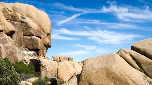 Low angle view of rocks against blue sky and clouds