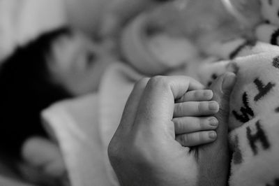 Close-up of baby holding hands on bed