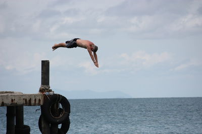 Man jumping in sea against sky