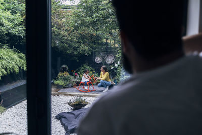 Man looking at family playing in back yard