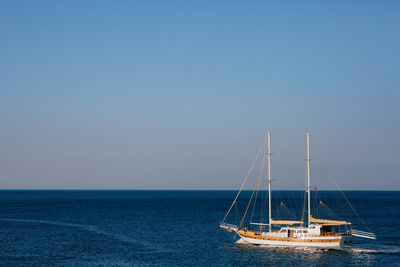 Sailboat sailing on sea against clear blue sky