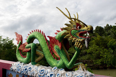 Close-up of dragon statue on tree against sky