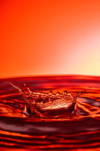 Close-up of splashing water against orange background