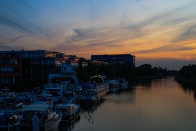 Boats moored at harbor against sky during sunset