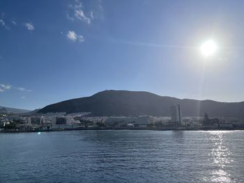 Sea by mountains against sky