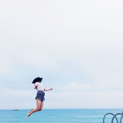 Young woman jumping against sea