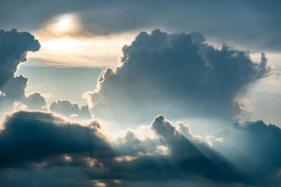 Low angle view of sunlight streaming through clouds