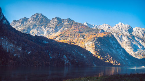 Scenic view of lake and mountains against blue sky
