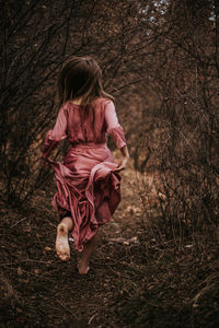 Girl with pink petals on tree in forest