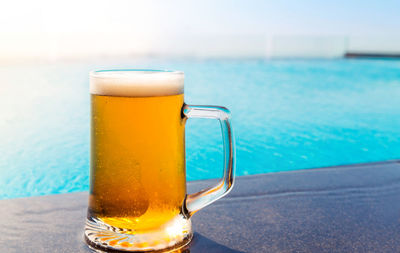 Beer glass on table by swimming pool
