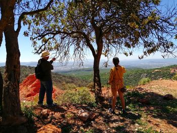 Friends standing by tree against sky