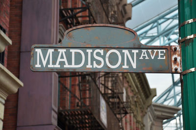 Low angle view of madison avenue sign against buildings in city