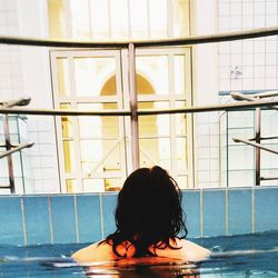 Rear view of woman sitting in swimming pool