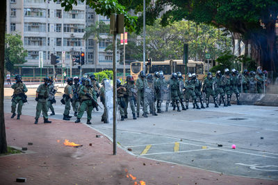 People standing on street against trees in city