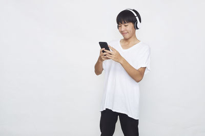 Young man using mobile phone against white background