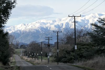 Snow covered road by mountains against sky