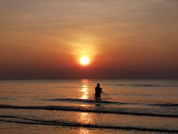 Silhouette woman standing at beach against sky during sunset