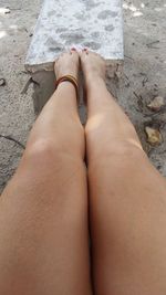 Low section of woman sitting at beach with legs on groyne