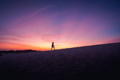 Silhouette man on desert against sky during sunset