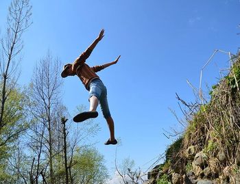 Low angle view of woman jumping in sky