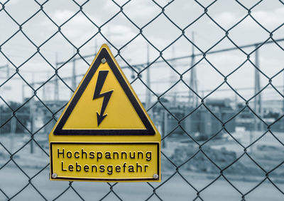 Close-up of warning sign on chainlink fence