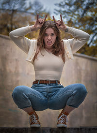 Full length of young woman sitting outdoors