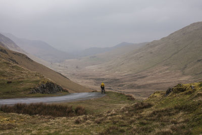 Man riding bike on mountain against sky