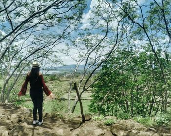 Woman walking on road amidst trees